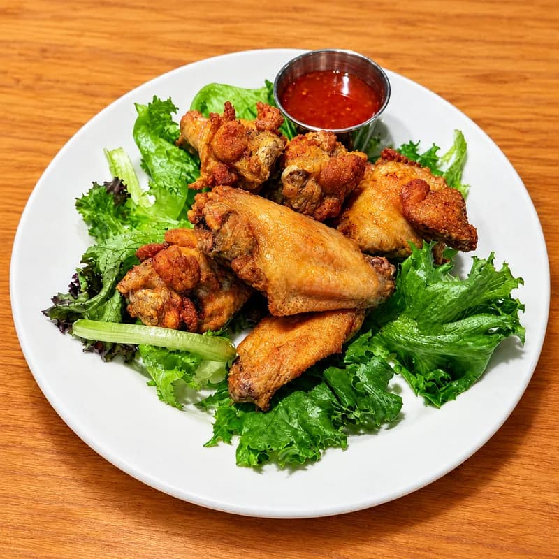 Crispy fried chicken wings on lettuce with dipping sauce